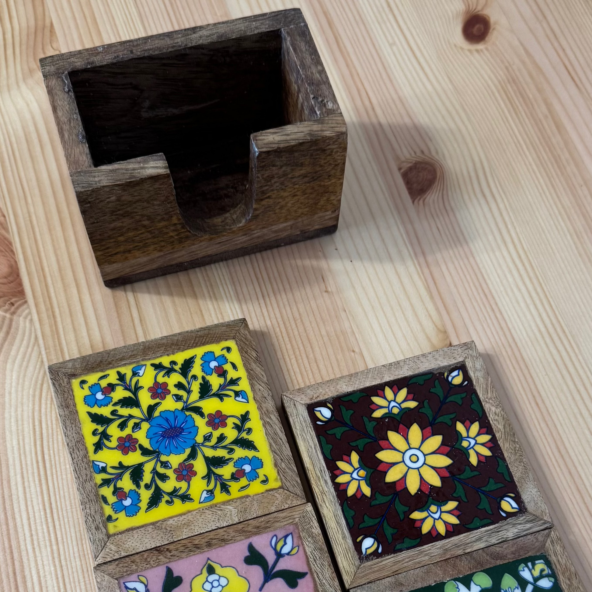 Four wooden coasters with floral designs on a wooden surface