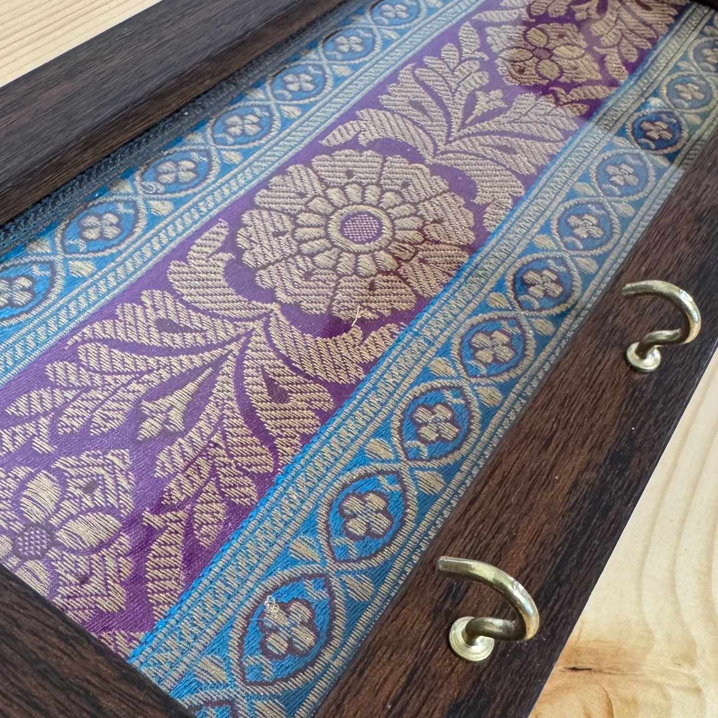 Wooden key holder with a blue purple brocade fabric cover.