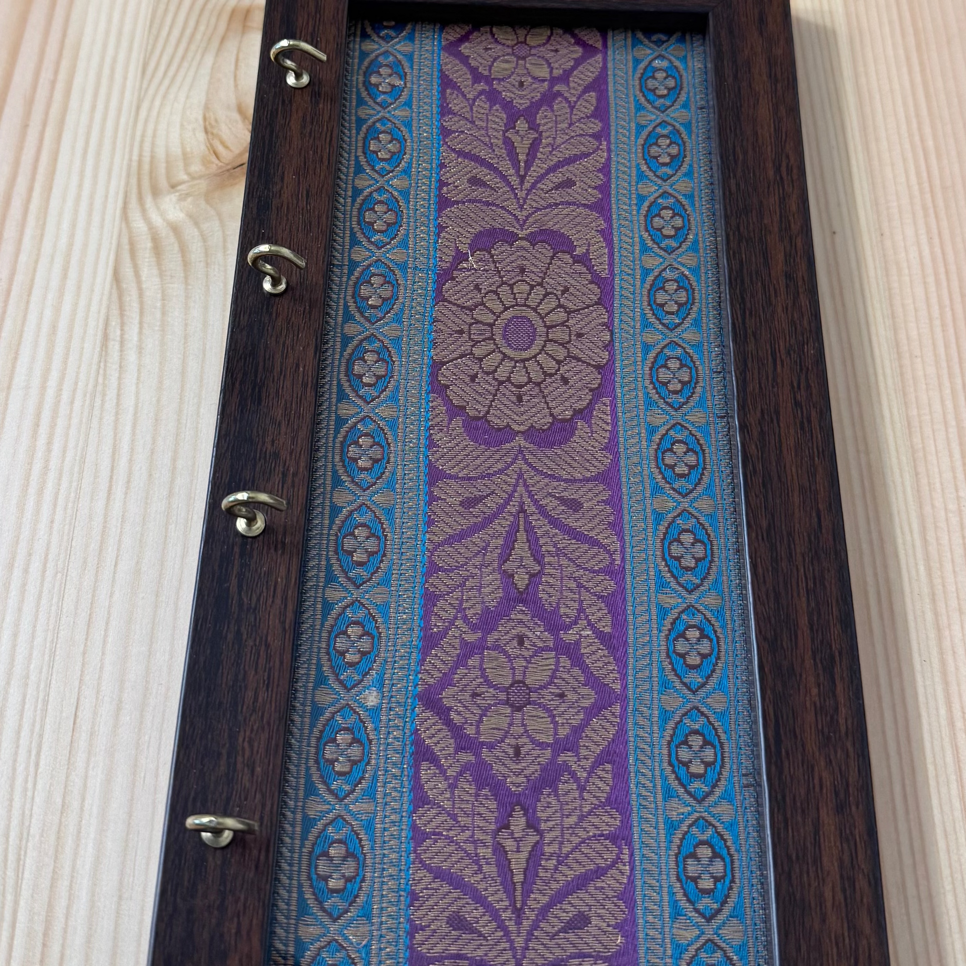Wooden picture frame with fabric inserts on a light wood surface
