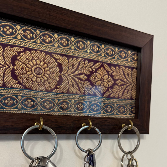 Key holder with keys hanging on a wall, featuring brocade fabric in the background.
