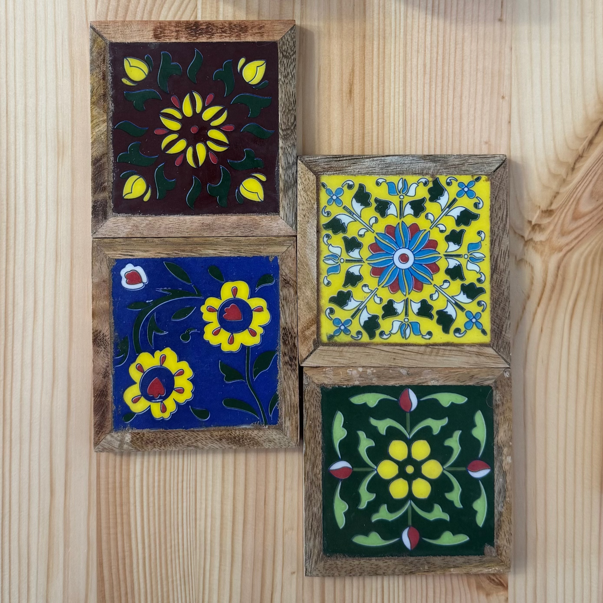 Set of four decorative coasters with floral patterns on a wooden surface
