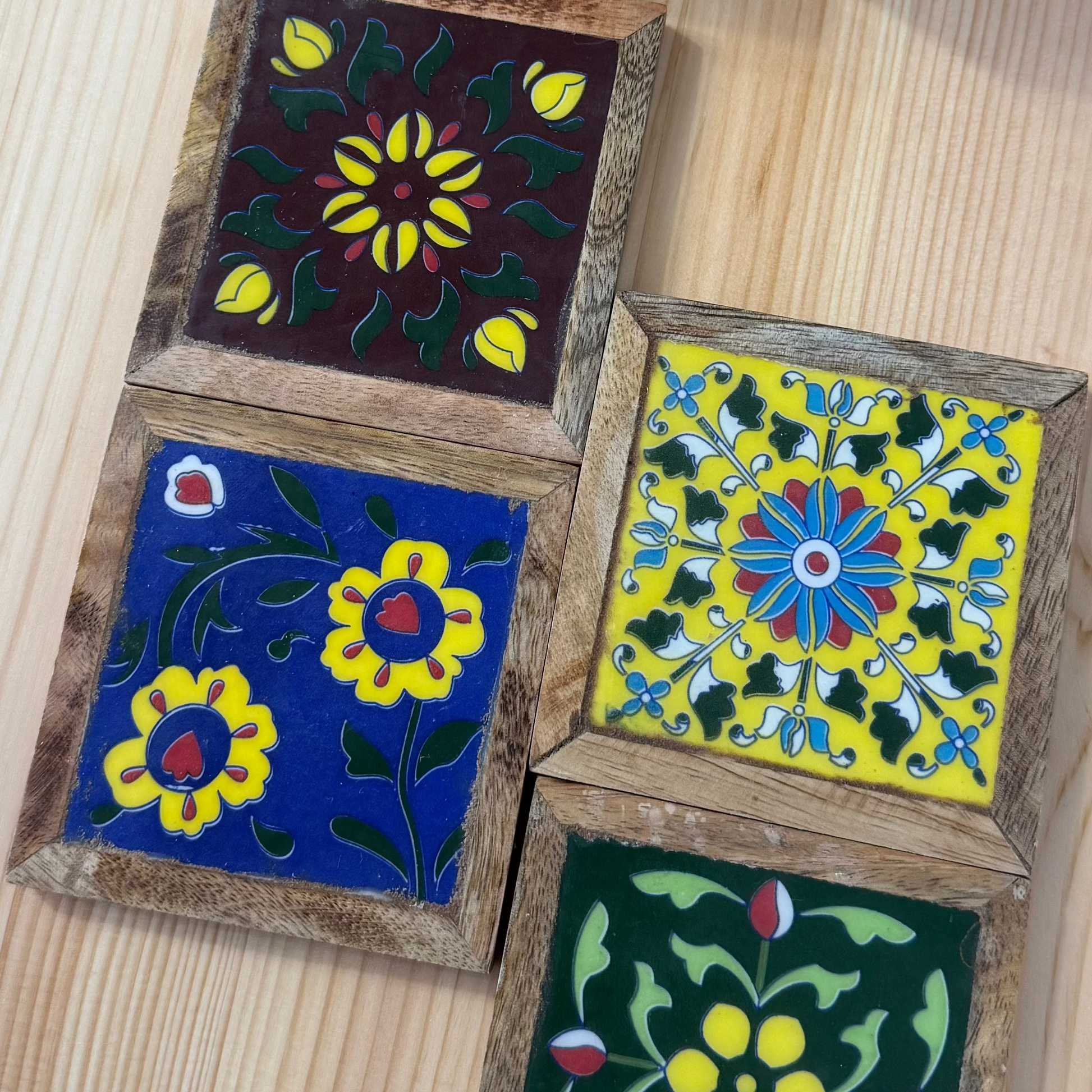 Four wooden coasters with floral designs on a wooden surface