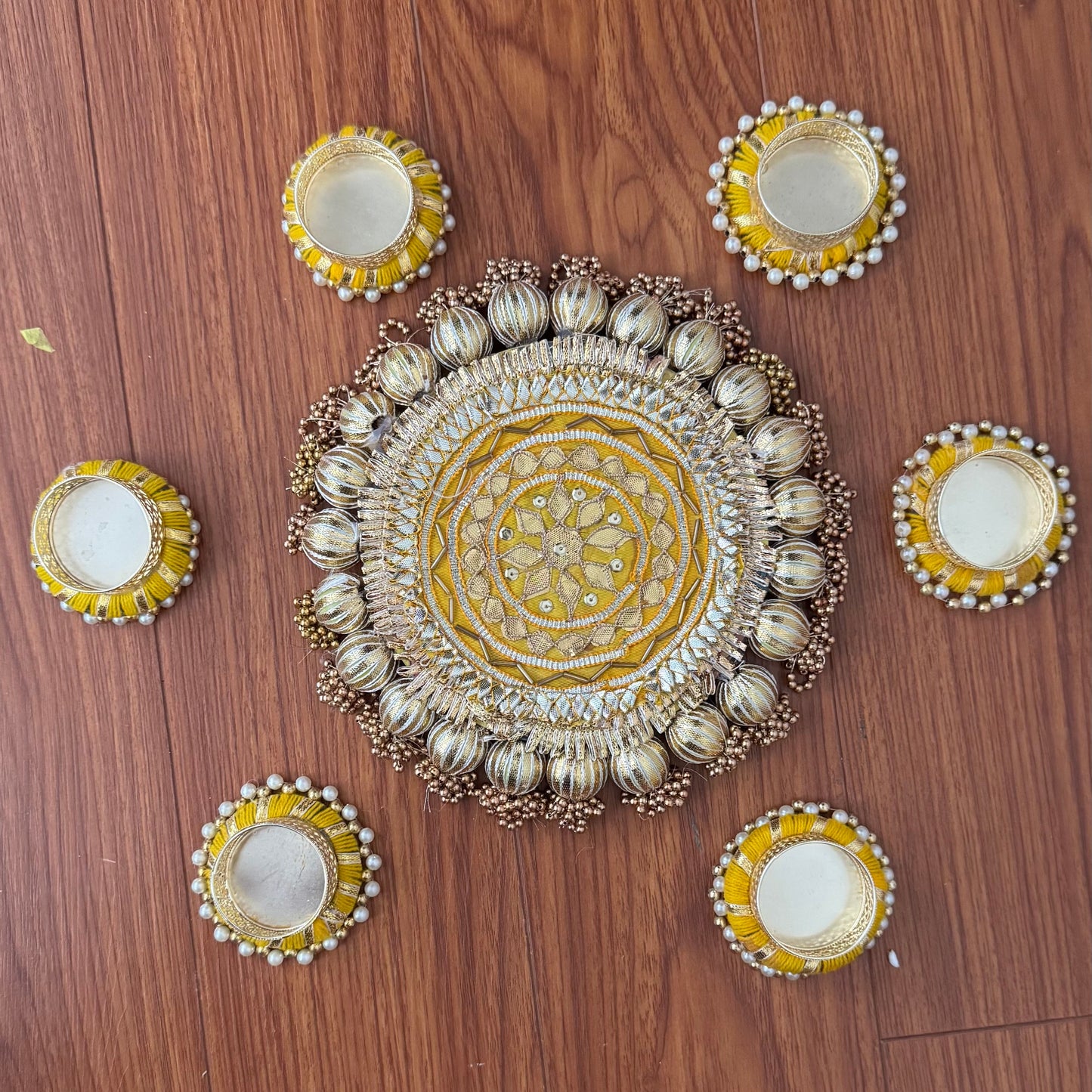 Decorative rangoli mat with intricate design on a wooden floor