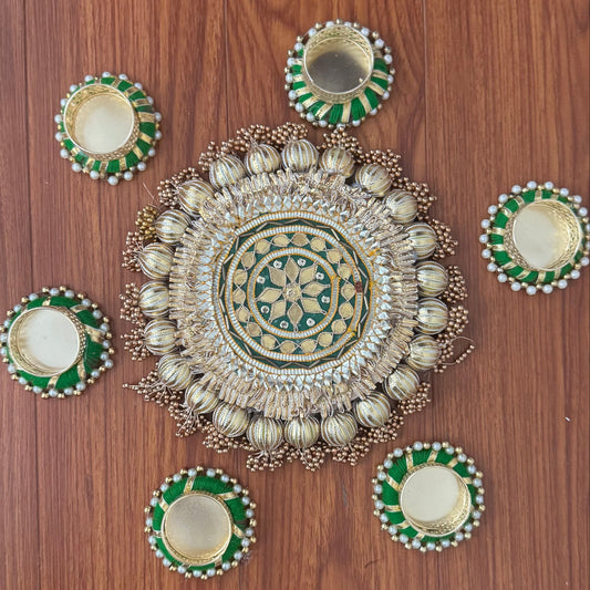 Decorative rangoli design on a wooden floor with green and gold elements.