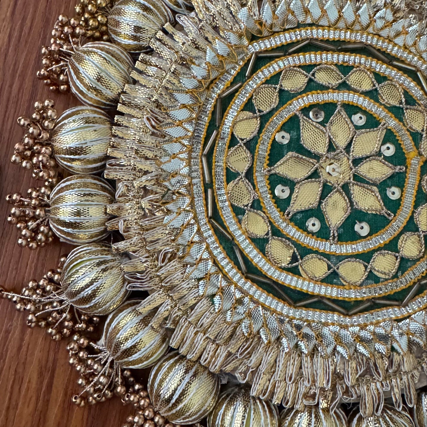 Ornate fabric rangoli piece with intricate designs on a wooden surface