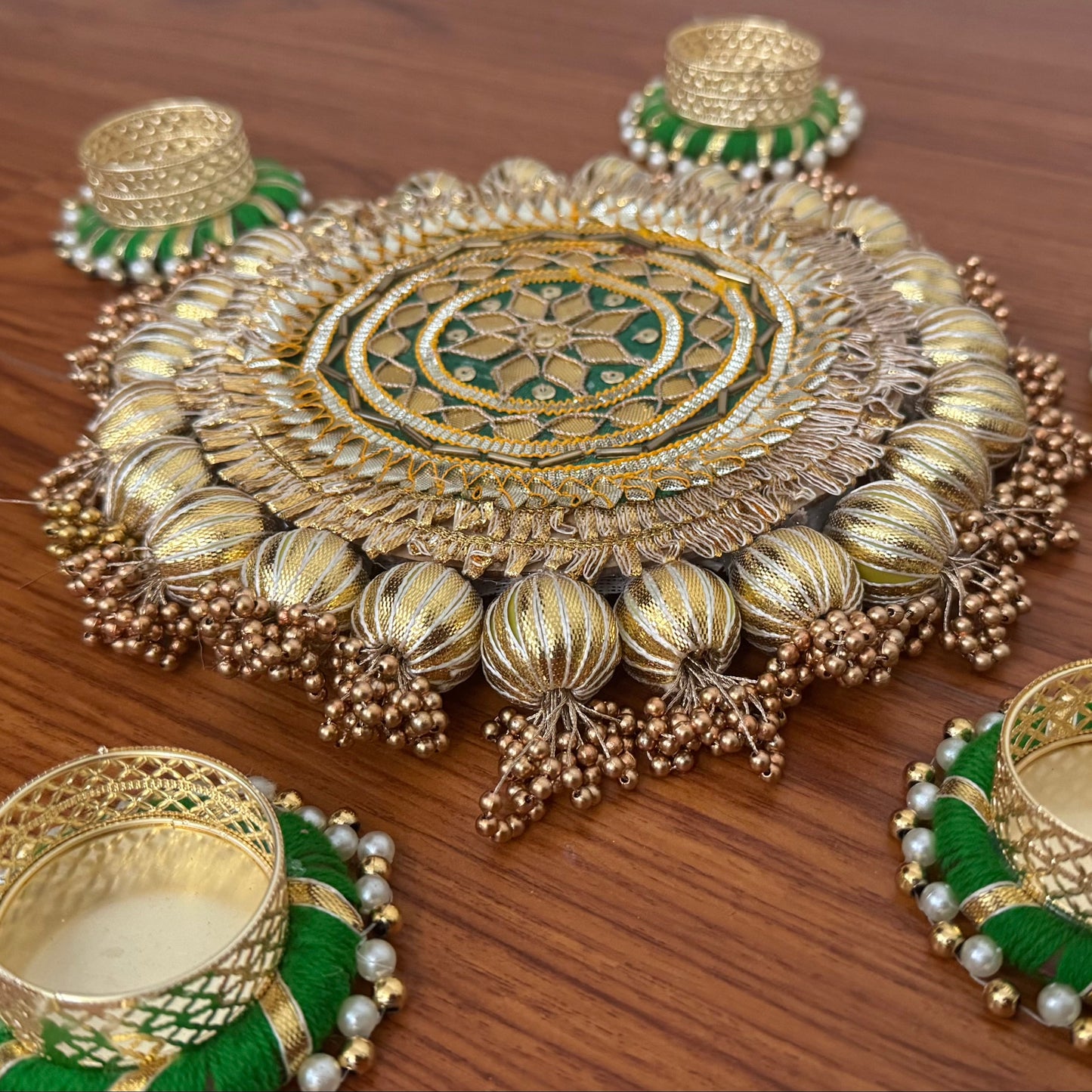 Set of gold and green tea light holder on a wooden surface