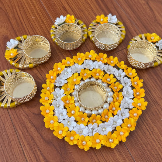 Decorative yellow and white flower arrangement with gold tea light holders.