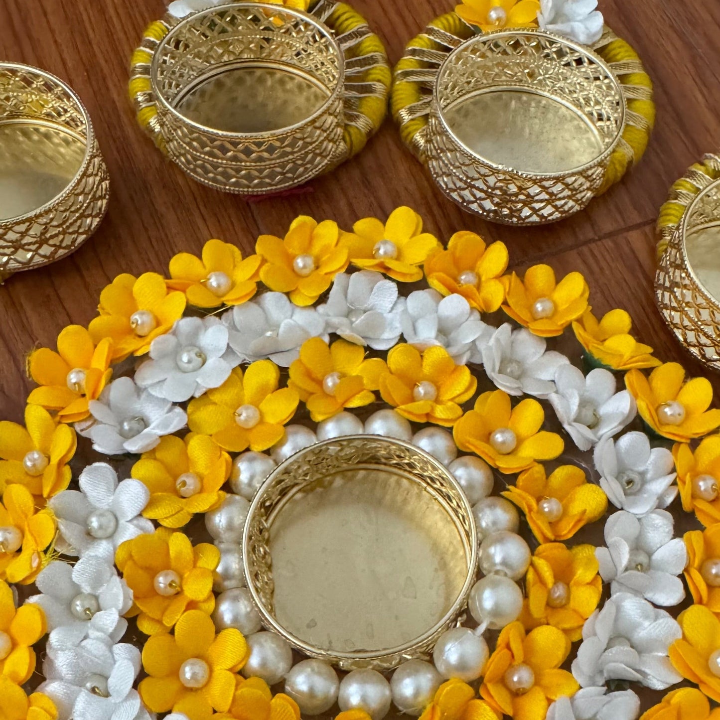 Decorative floral rangoli arrangement with yellow and white flowers.