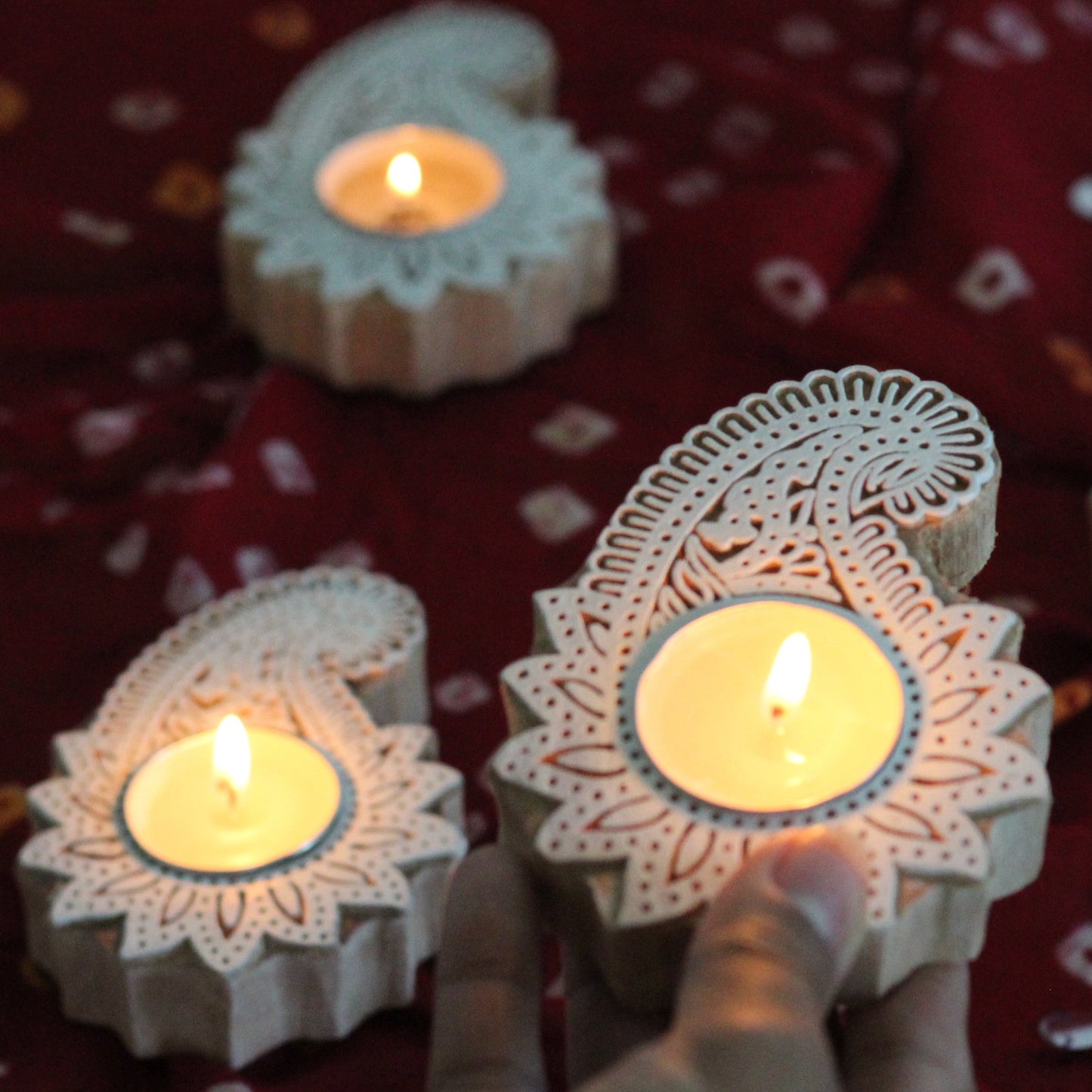 Decorative paisley candle holders with intricate designs on a red fabric background