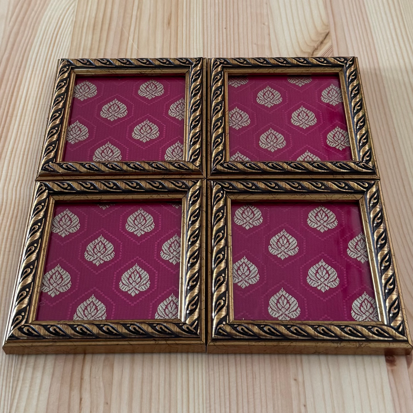 Decorative brocade fabric coaster with pink and gold pattern on a wooden surface.