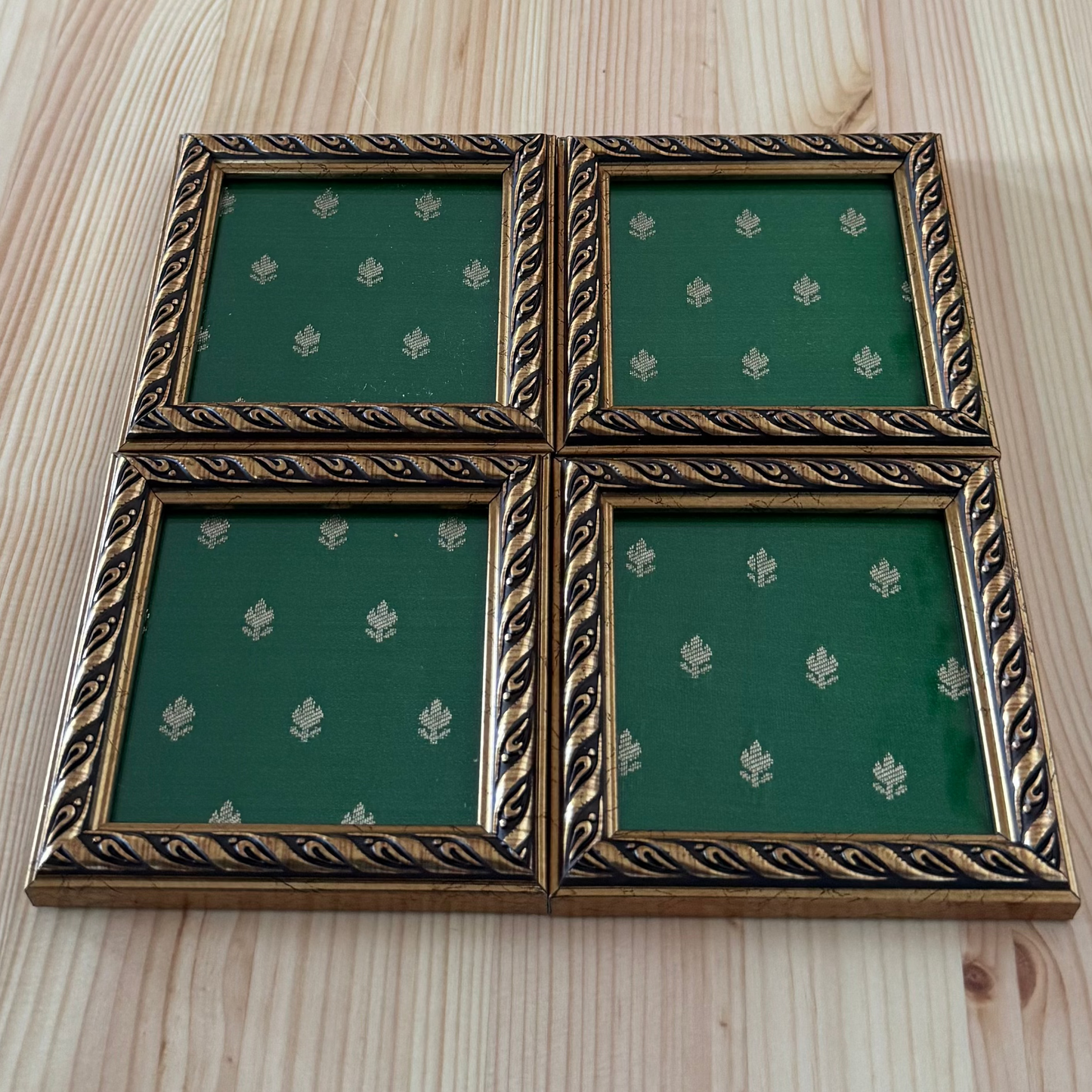 Brocade Fabric coaster with green fabric and gold trim on a wooden surface